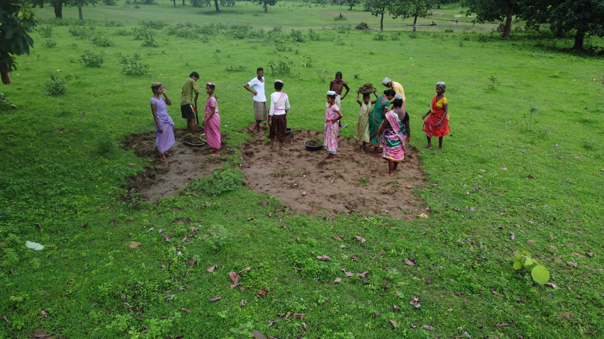 A rural community gathered in a green field in India; illustrative photograph
